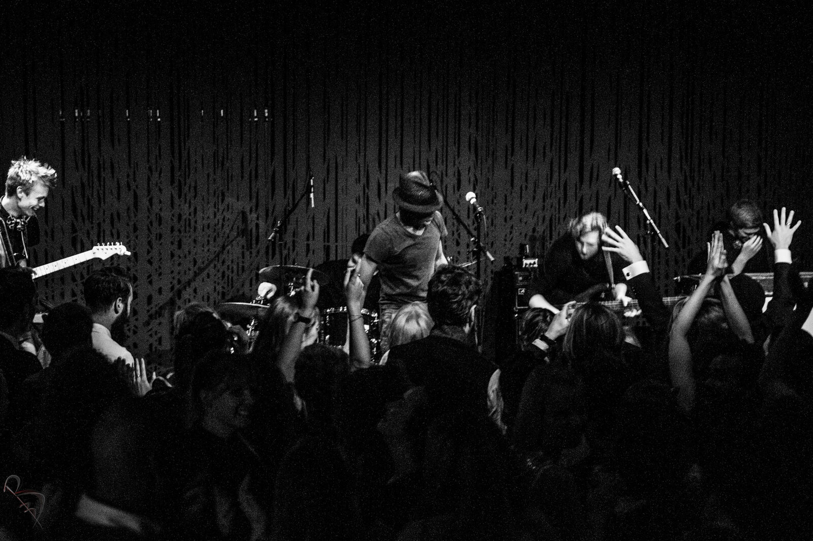 Black and white photo of a crowd with raised hands at an Elvic Kongolo concert