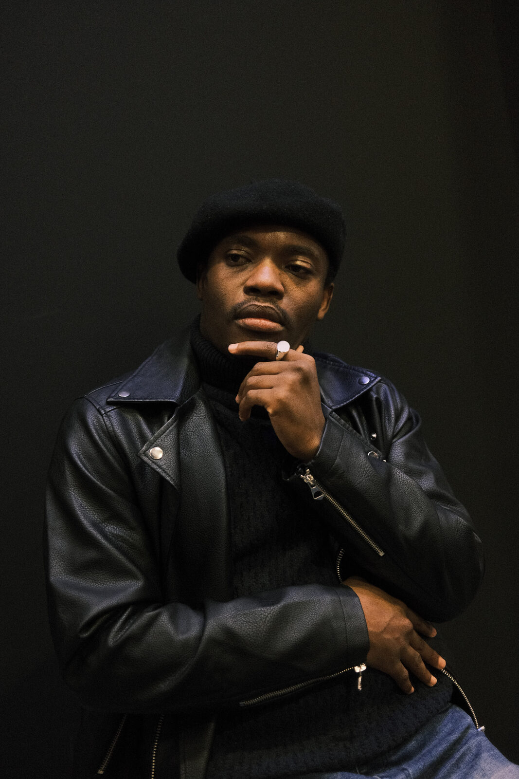 Elvic Kongolo in a black leather jacket against a dark background